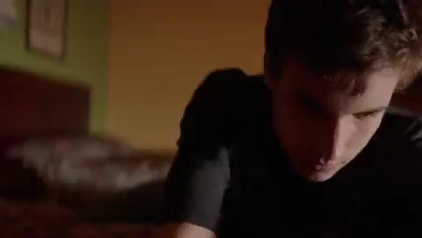 A man is sitting on the edge of a bed in a room with flashing lights