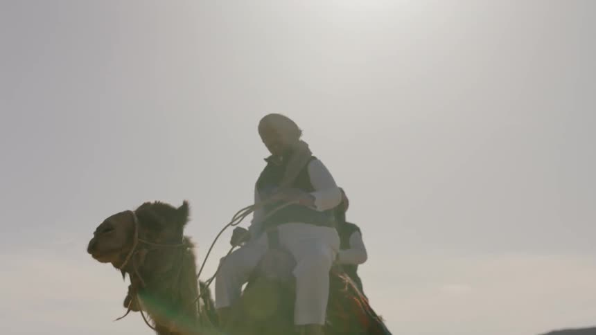 Two men are riding camels