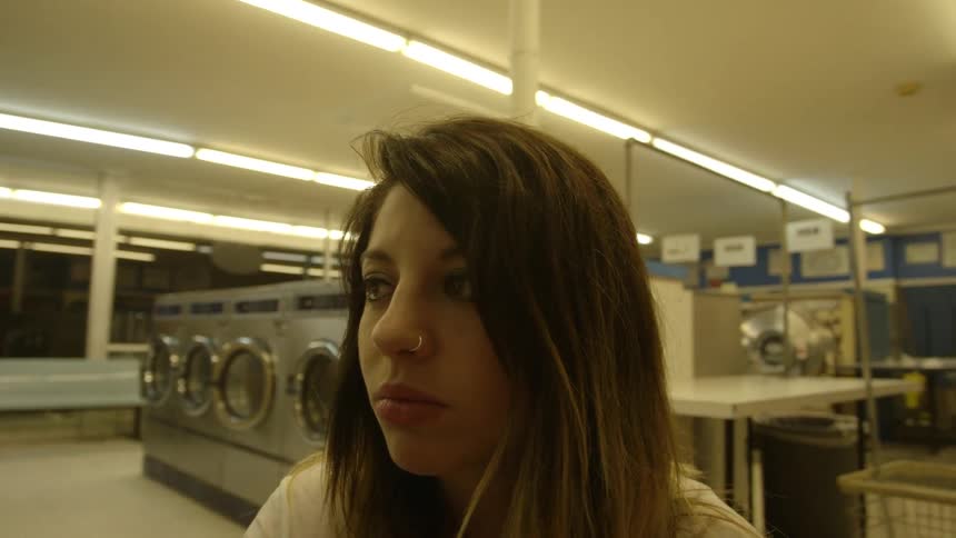 A woman is pushing a cart inside a laundromat