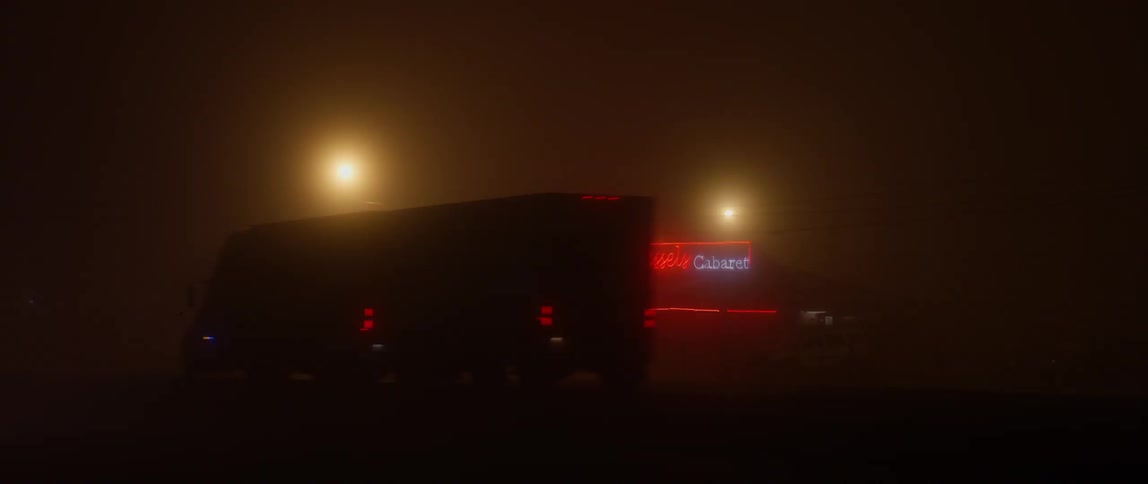 Vehicles driving past a neon lit building at night