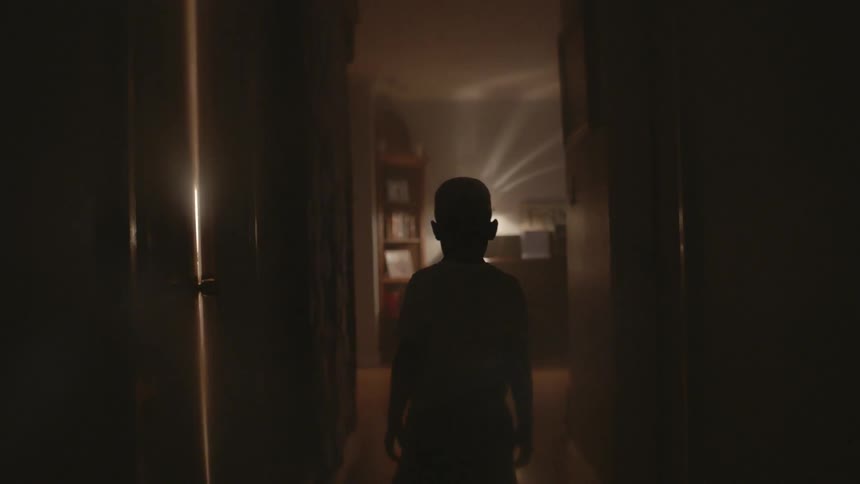 A young boy walks down a hallway