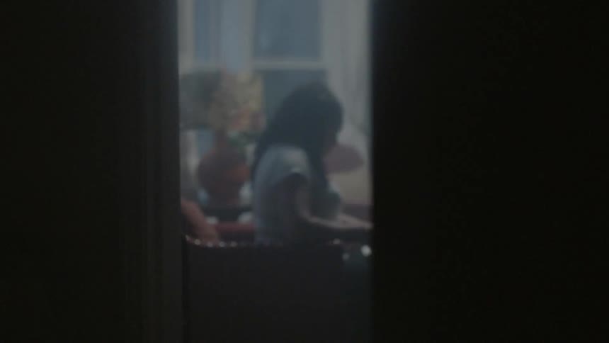 A woman is sitting in the room ahead