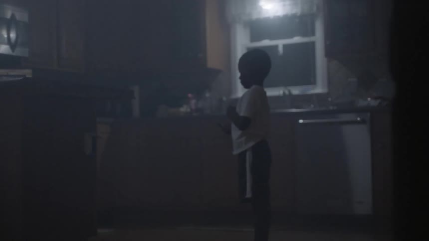A boy stands in a kitchen