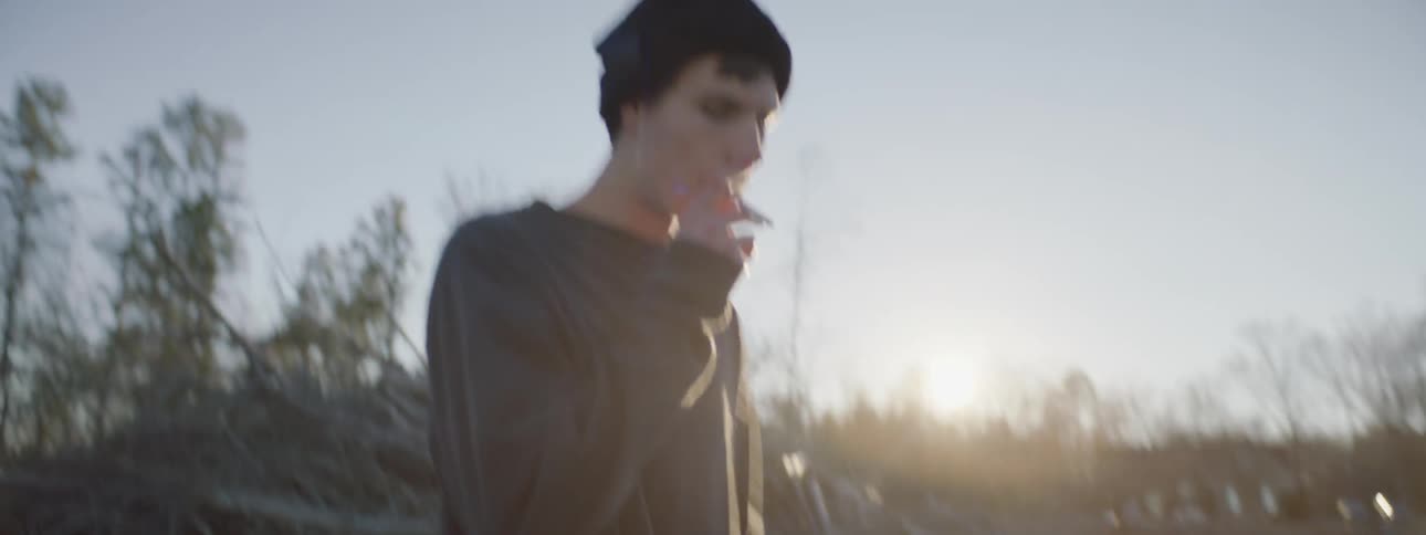 A young boy is smoking and pacing in a field