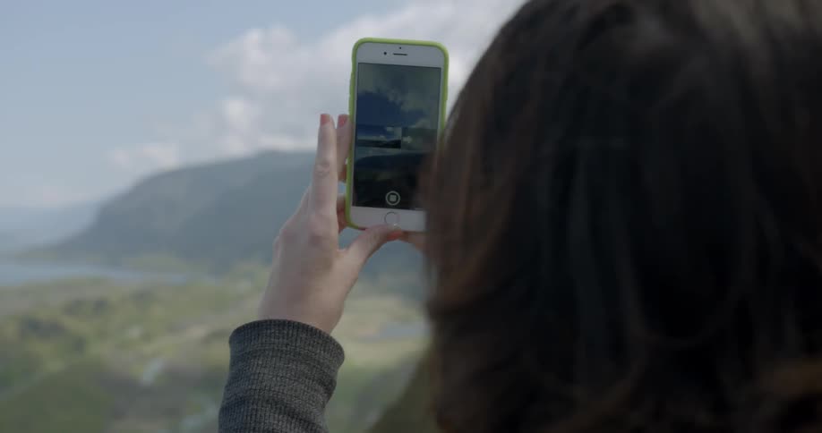 A woman using her smartphone to photograph the scenery