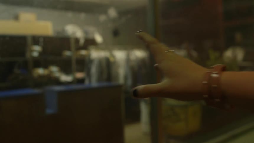 A woman walks away from a window with her hand out