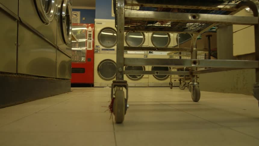 A person pushes a laundry cart in a laundromat