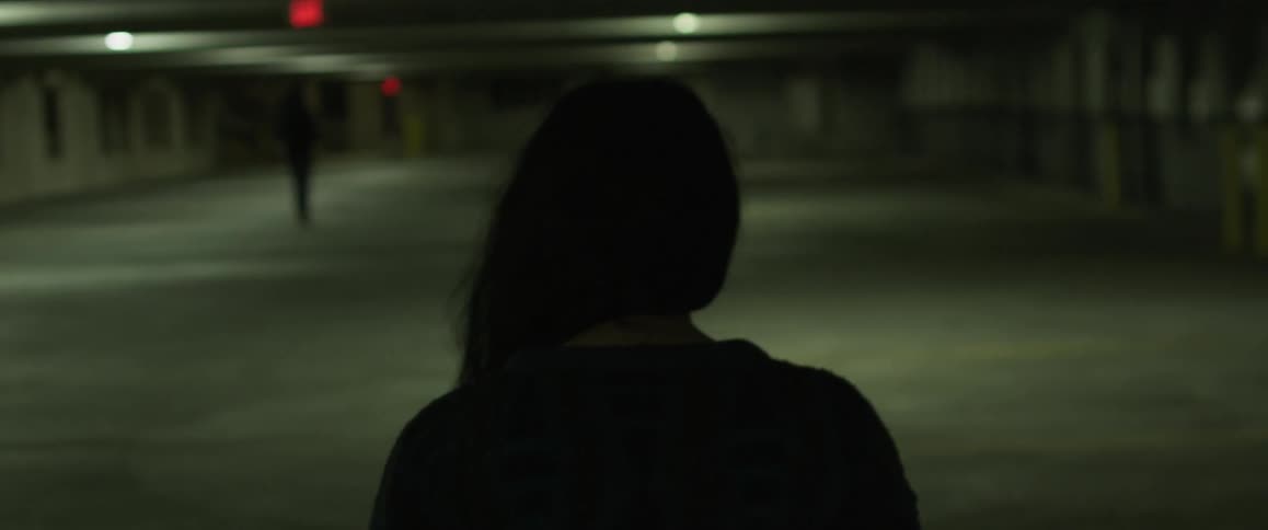 Woman walks in a parking ramp at night