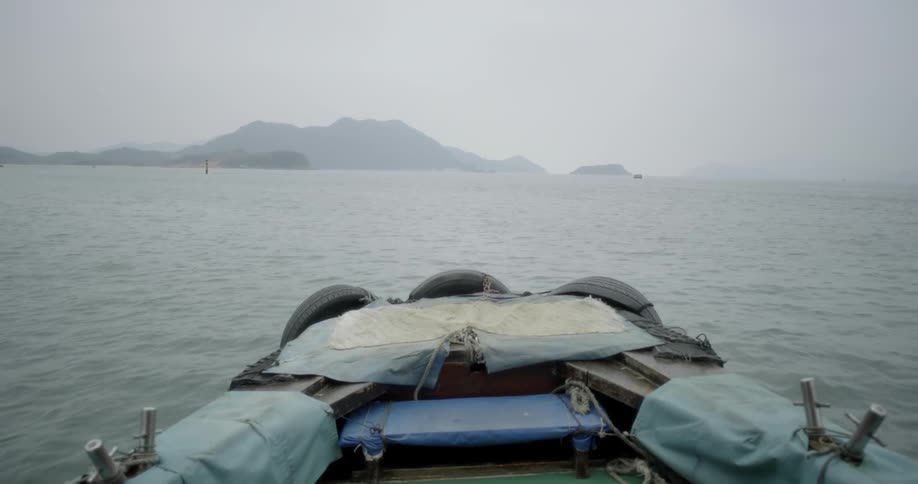 A boat is travelling over the open ocean to a rocky island