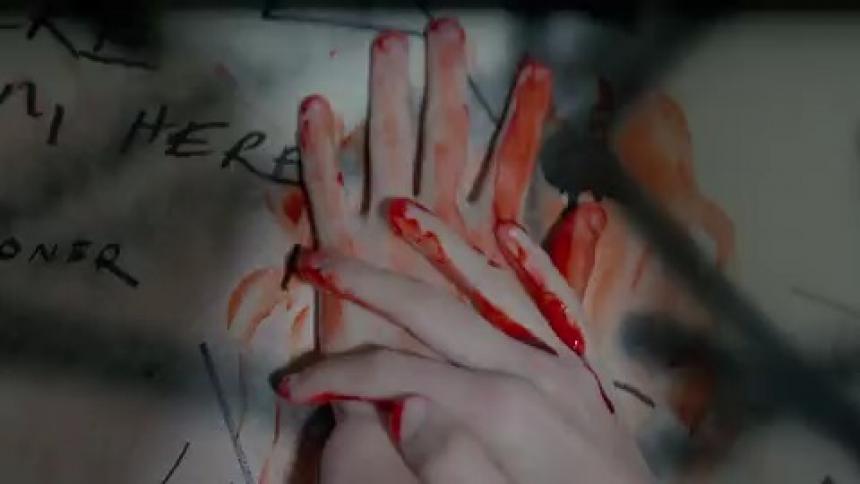 A person with blood on their hands is smearing it on a wall