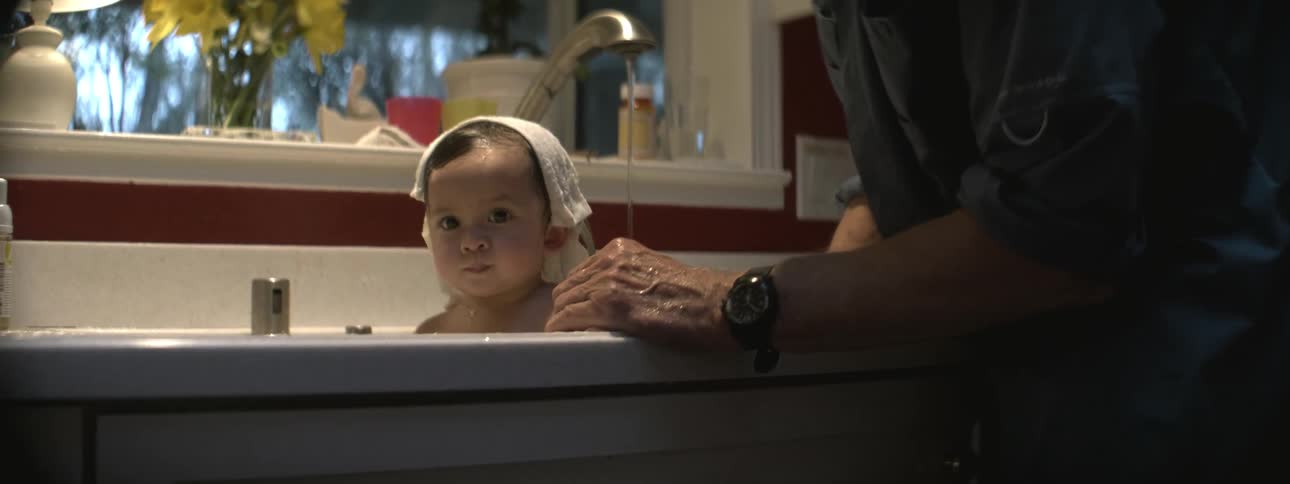 A man pours water over a bathing baby