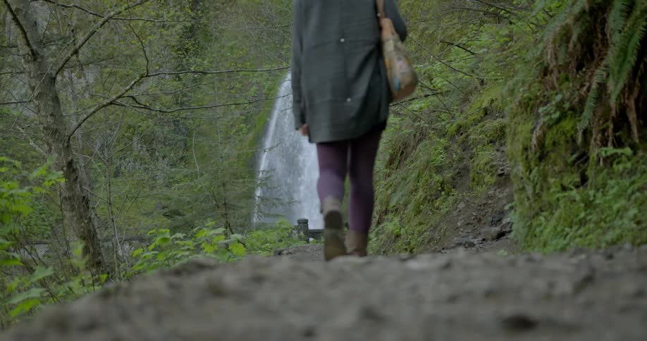 Woman walks to a cliff to see a waterfall ahead