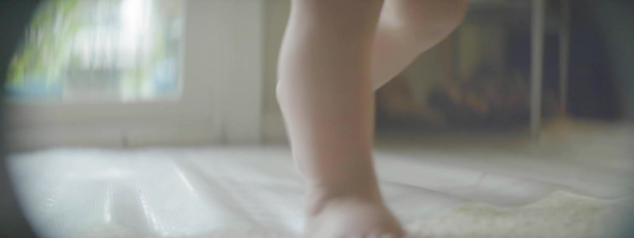 A baby is walking in a living room