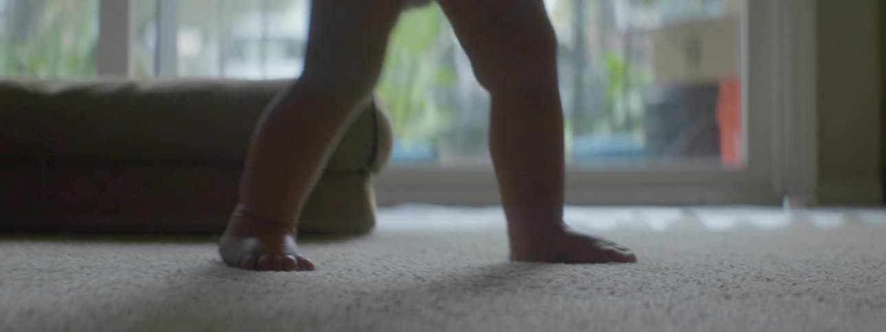 A toddler is walking in the living room