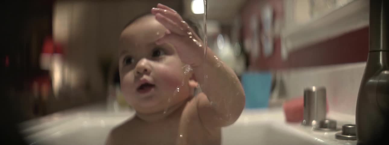 A baby is bathing in the sink