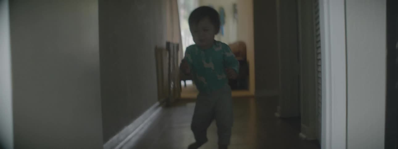 A toddling baby walks through a hallway in a home