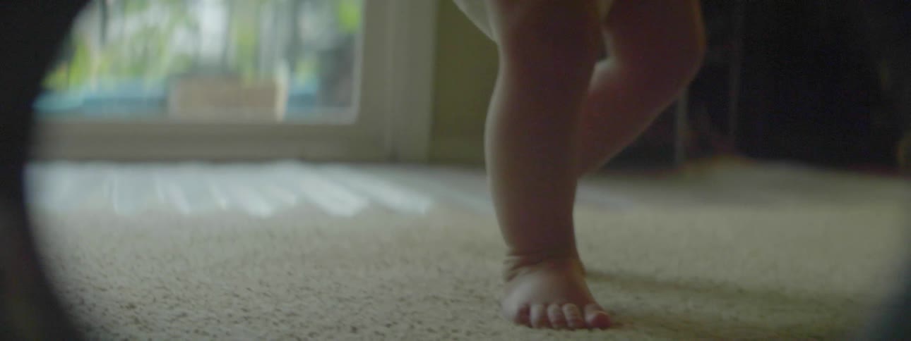 A toddler near a dog stands up and walks away