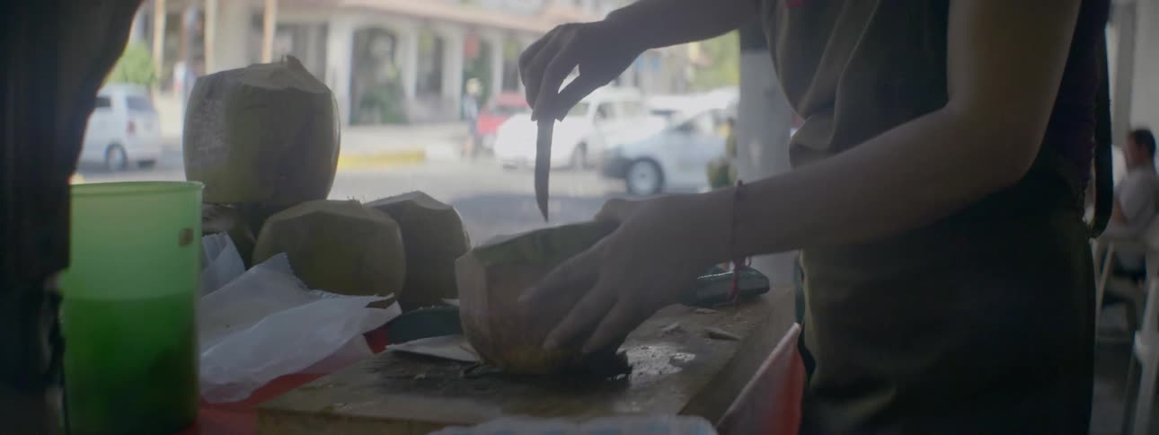 Person hacks at a fruit with a large cleaver
