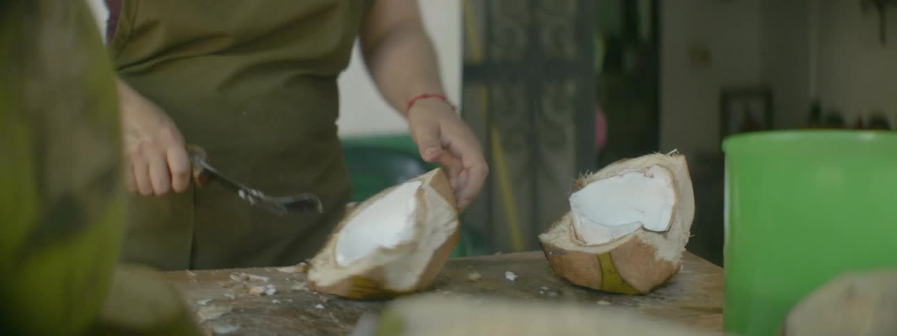 A man is cutting up a coconut