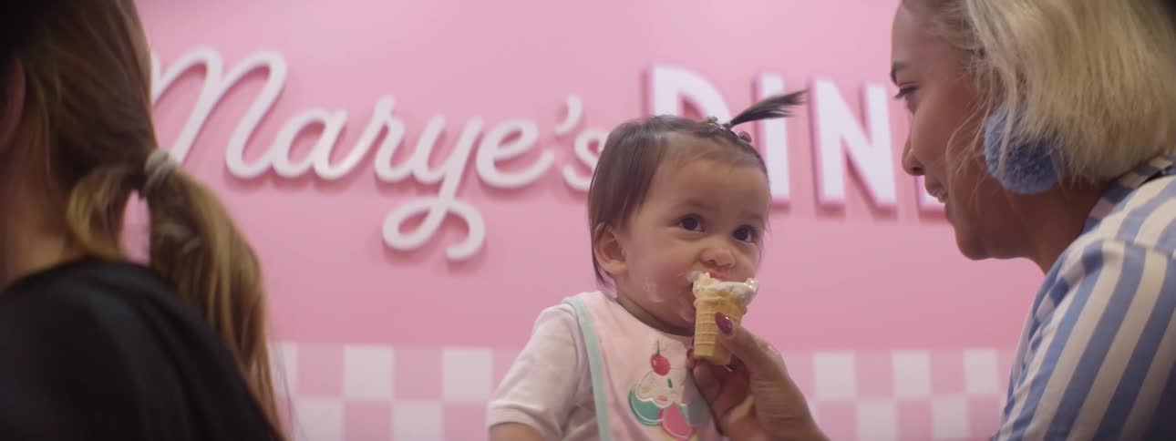 A woman wipes a baby's face and feed it ice-cream