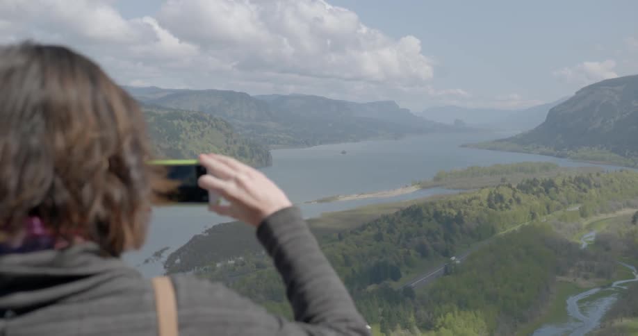 A woman trying to capture the panoramic view of the lake and the mountains