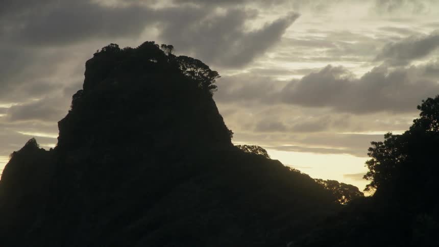 Clouds float over a mountain peak at sunset