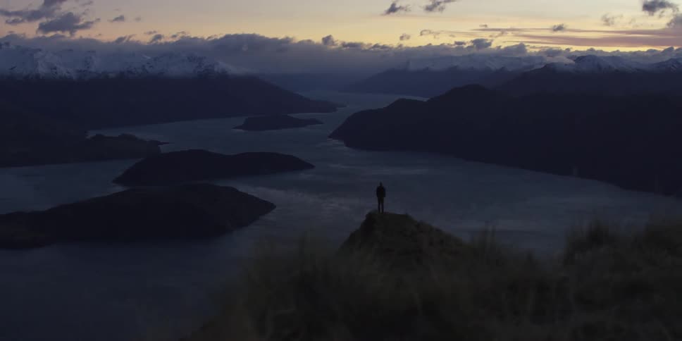 A man is standing on a peak at sunset
