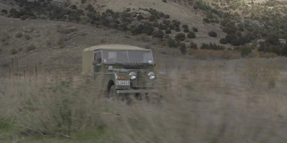 A green jeep drives down a dirt road