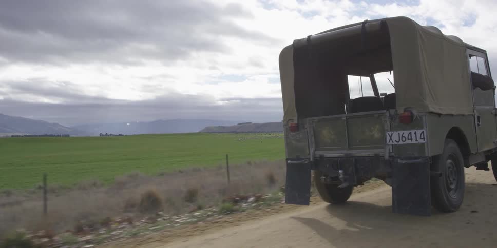 A green jeep drives down a dirt road