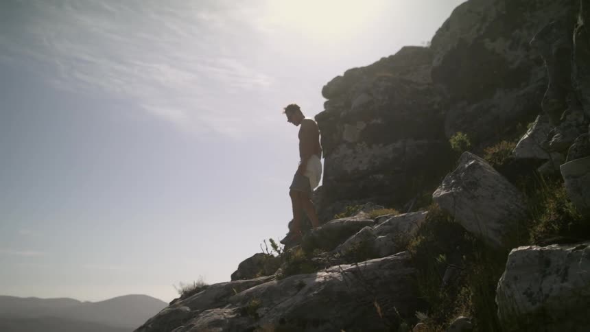 A man walks down a rocky ledge