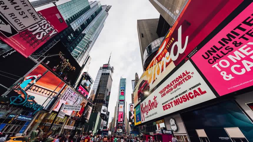 A busy city street is being filmed in a time lapse full of billboards