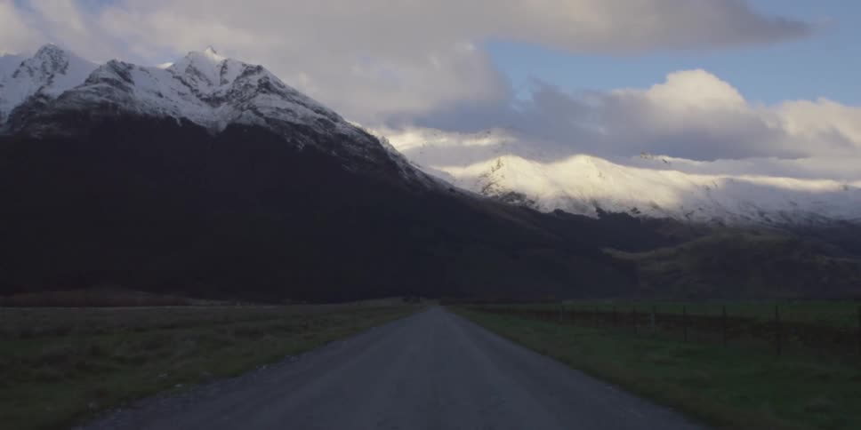 Driving down a road towards a snow covered mountain