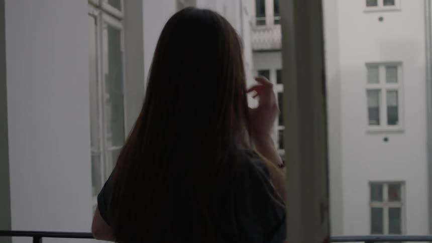 A woman sips coffee on an apartment balcony