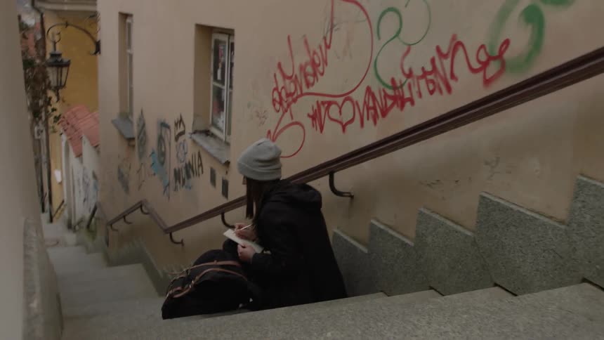 A woman sits on the steps in an alley