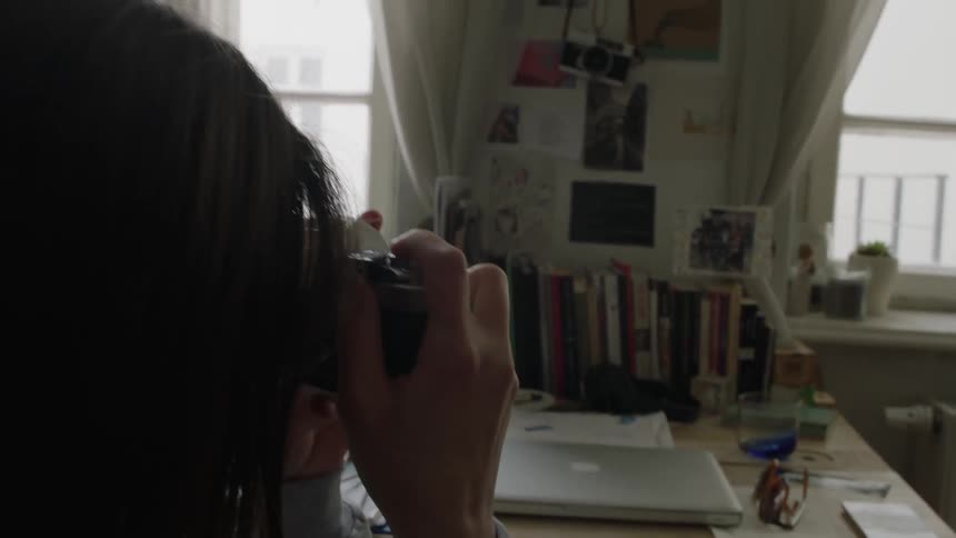 A woman sits at a desk and takes a picture
