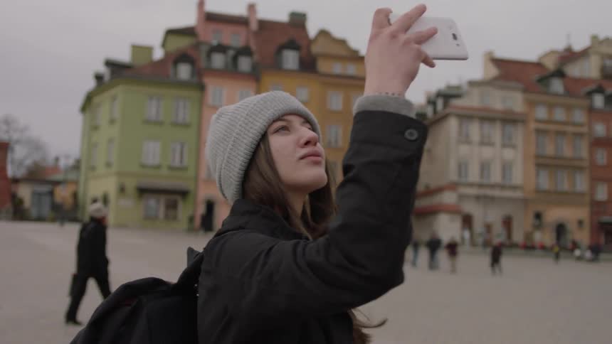 A woman stands outside and takes a picture