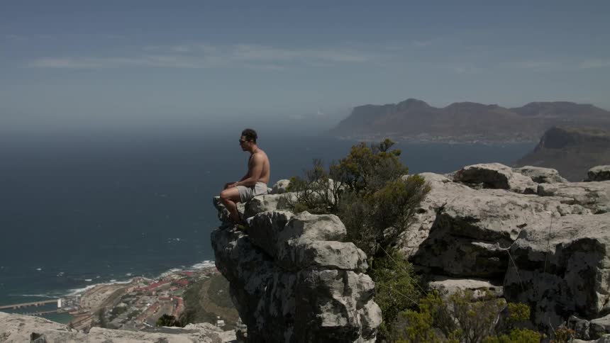 Man sitting on a rocky cliff overlooking water