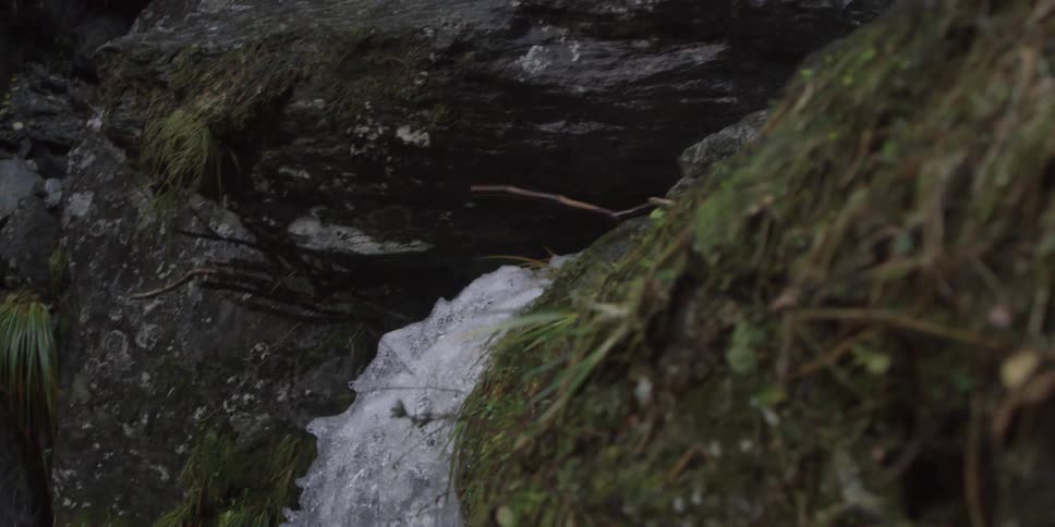 Water travels down a small waterfall into a river below