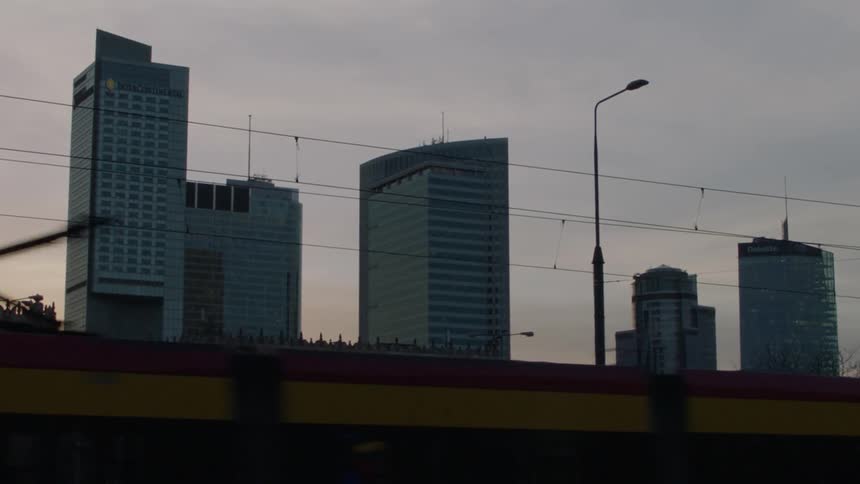 Buildings standing tall before a public mass-transit vehicle passes before them