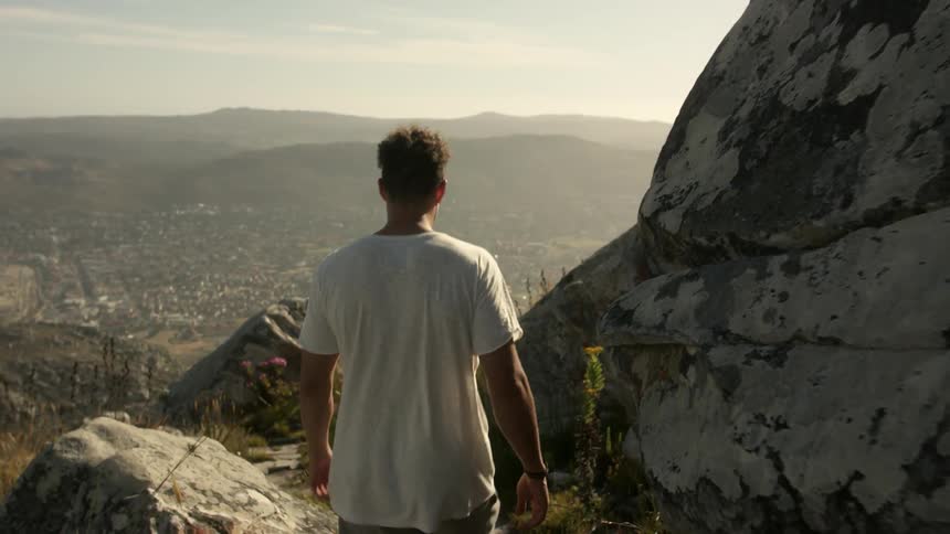 A man walks toward a rocky edge