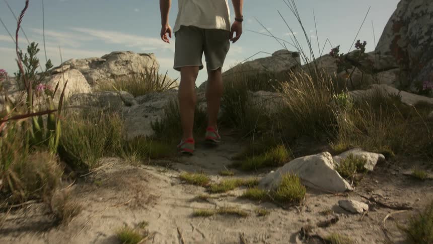 A man is walking through the desert to a ridge overlooking a valley