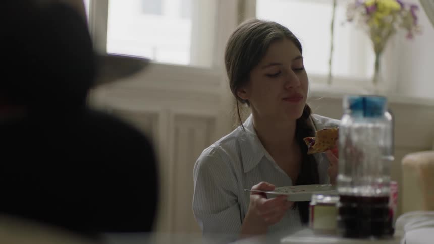 A woman eats while talking with someone
