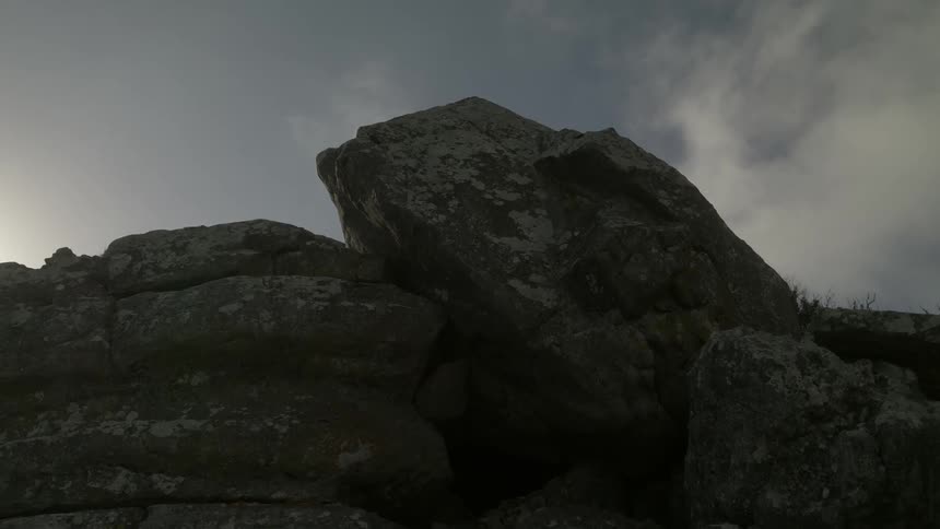 The sun sets behind the large rocks above