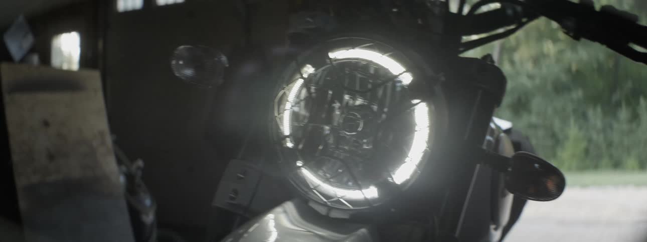 The headlight shines on a motorcycle in a garage
