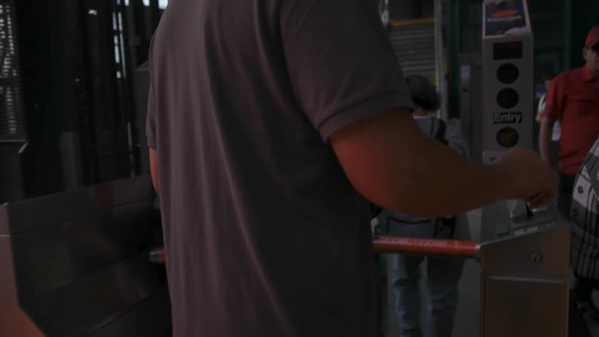 A man scans his card as he goes through a subway turnstile