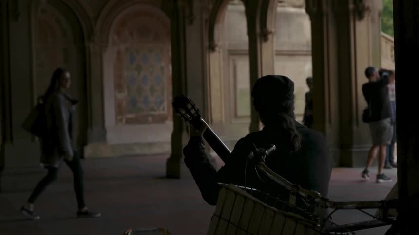 A man plays music for passing people