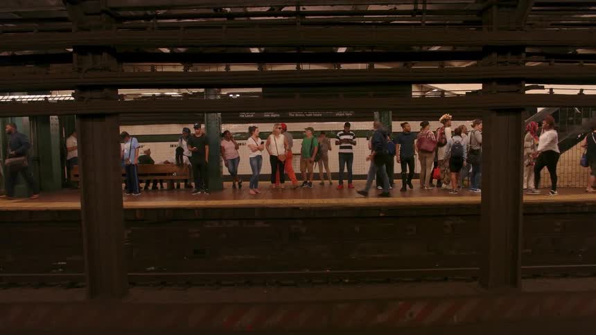 Subway trains pass as people wait