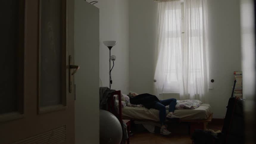 A woman enters her bedroom and jumps on the bed