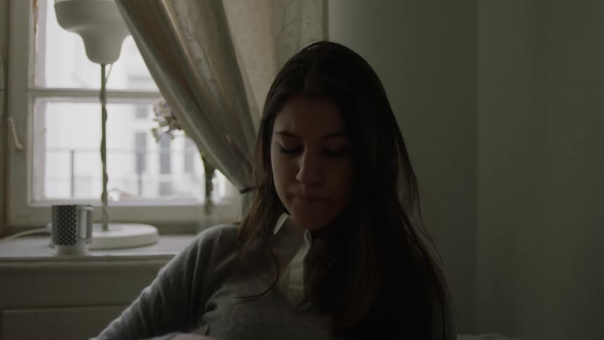 A woman drinks from a mug and holds a notebook