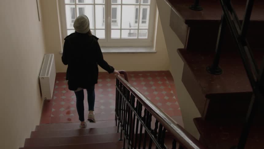 Woman goes down the stairs holding the banister